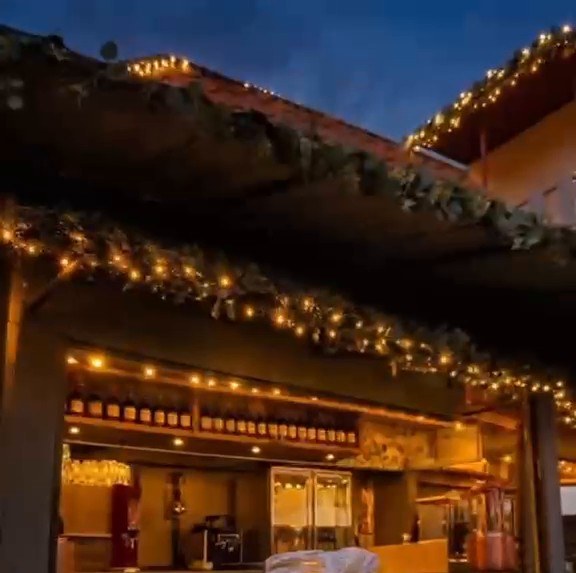 Die Alm am Abend mit Lichterketten und Glühweintassen